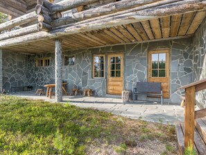 A stone building with a wooden porch, stone walls, and a bench. - Kiela 1 by Interhome (Inari)