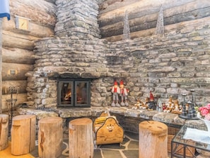 A log cabin interior with a stone fireplace, wooden stools, and rustic decorations. - Kiela 1 by Interhome (Inari)