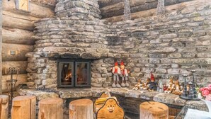 Un interior rústico de piedra con chimenea, taburetes de madera y figuras decorativas de gnomos.