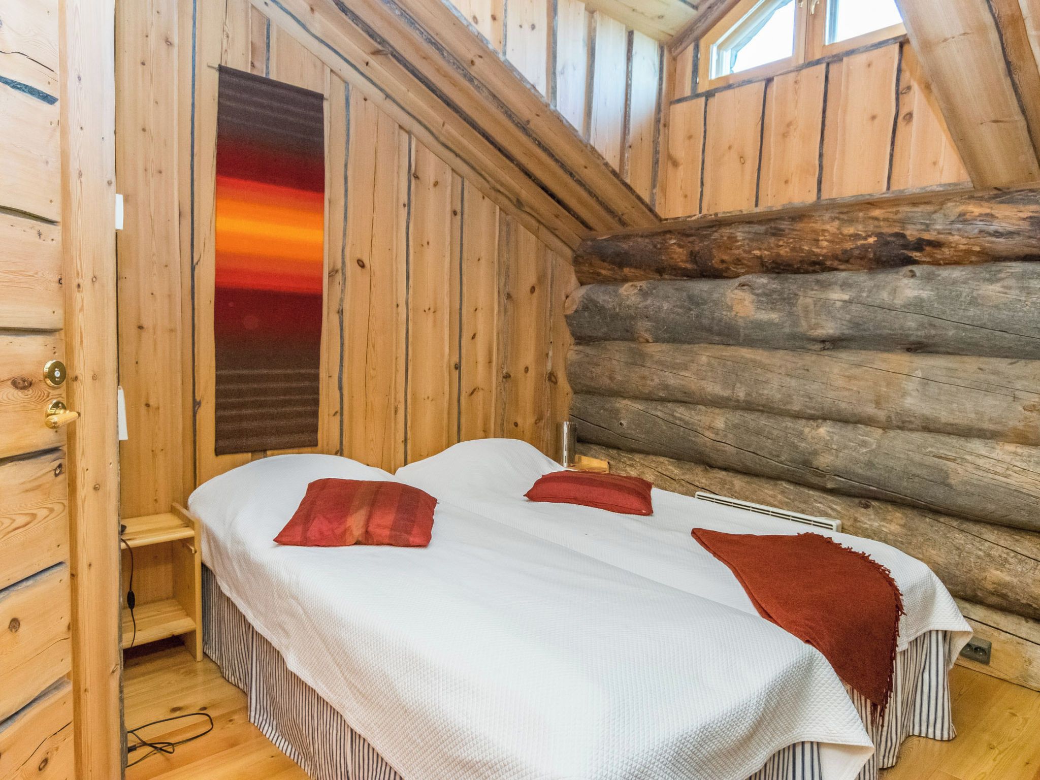 Une cabane avec un lit, une fenêtre et un mur en rondins.