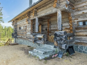 Une cabane en rondins avec des fondations en pierre, une véranda dotée de piliers en bois et une fenêtre.