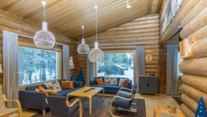 A log cabin interior with a sofa set, a coffee table, and a dining table.