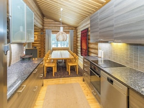 A modern kitchen with a wooden dining table and chairs, a built-in oven, and a stainless steel dishwasher.