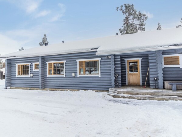 A log cabin with a front porch, a wooden door, and windows with shutters. - Govadas by Interhome (Inari)