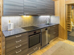 A modern kitchen with dark wood cabinetry, a stainless steel dishwasher, and a built-in oven. - Govadas by Interhome (Inari)