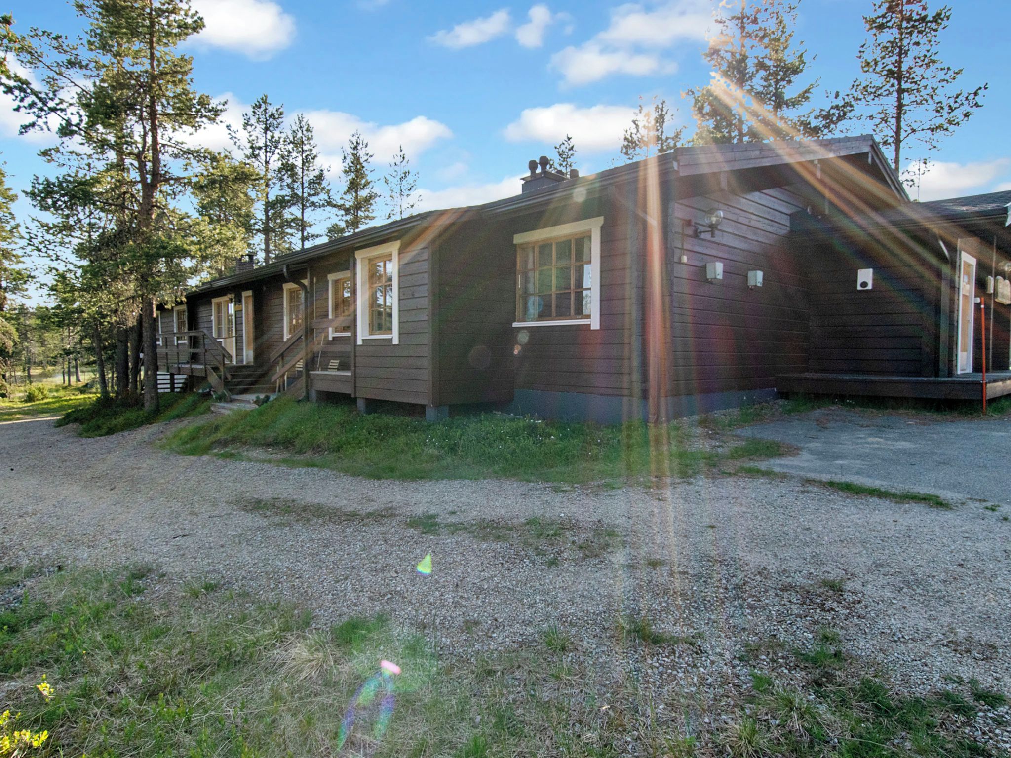 Eine zweistöckige Holzhütte mit Kiesauffahrt und einer Holzterrasse.
