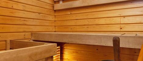 Uma sauna com bancos de madeira e um balde de metal.