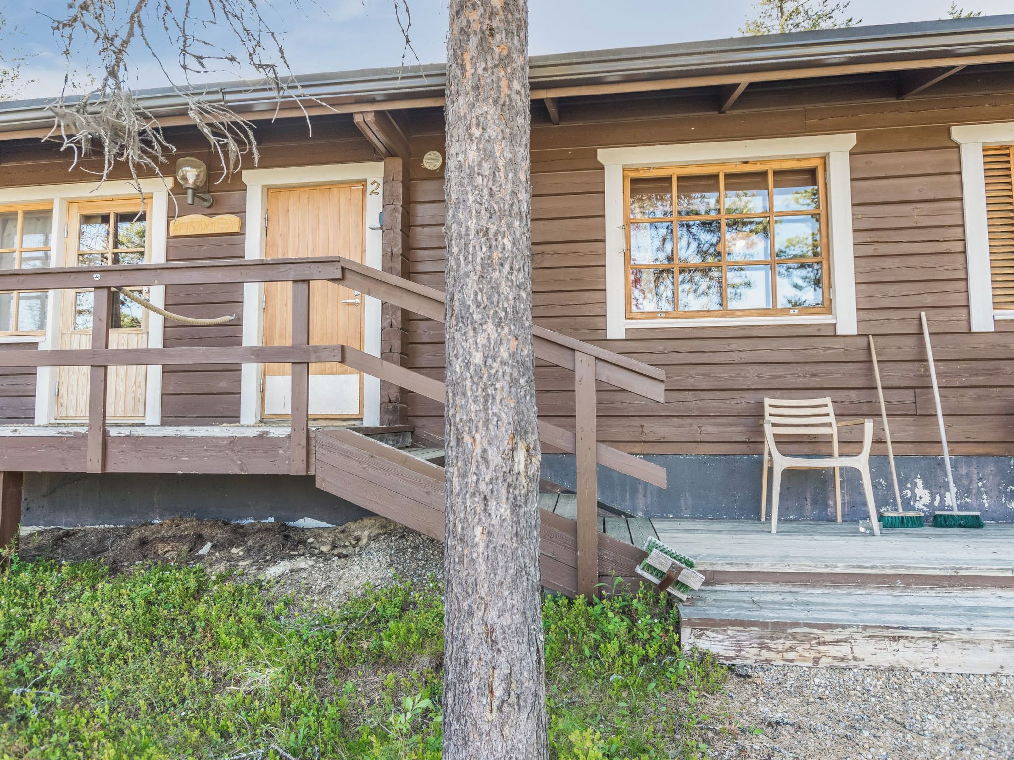 Une cabane en bois avec une véranda, un escalier et une fenêtre.