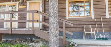 Une cabane en bois avec une véranda, un escalier et une fenêtre.