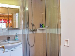 A bathroom with a glass-enclosed shower, a sink with a faucet, and a mirror above the sink. - Metsänpirtti 2 by Interhome (Inari)