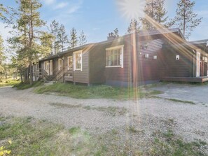 A cabin with a gravel driveway, wooden exterior, and a porch with steps leading to the entrance. - Metsänpirtti 2 by Interhome (Inari)