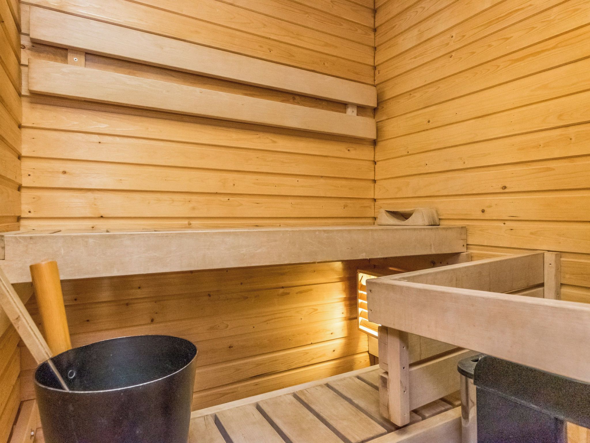 Eine Sauna mit Holzbänken und einem Eimer.