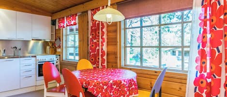 Ein Interieur einer Hütte mit Essbereich, Küche und großen Fenstern.