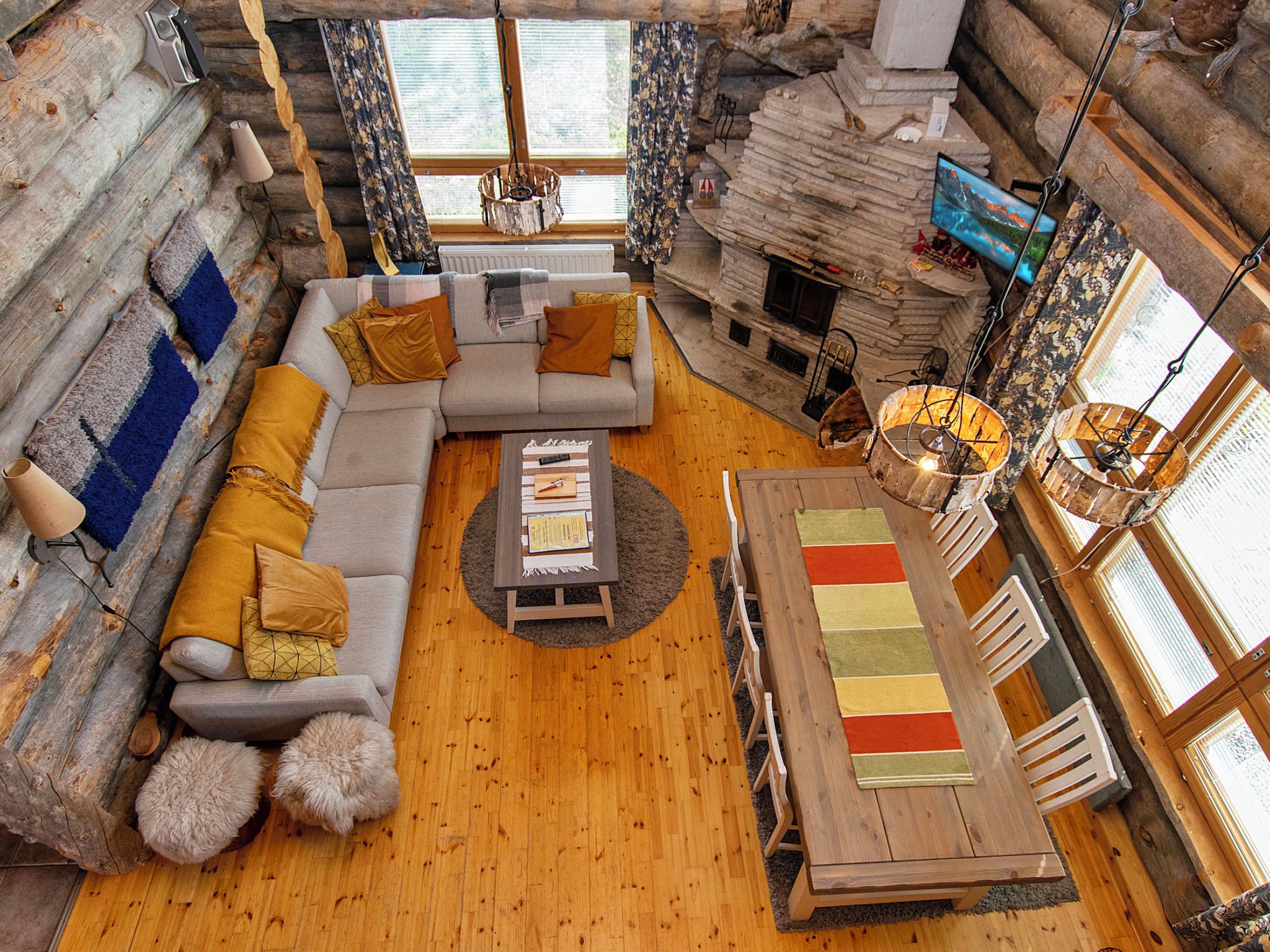 Un interior acogedor de cabaña de madera con sofá, mesa de centro, mesa de comedor y chimenea.