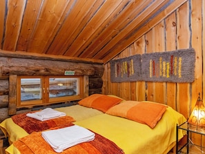 Une chambre rustique aménagée dans un chalet en rondins, comprenant un lit, deux serviettes, une fenêtre et une tapisserie murale.