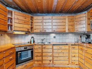 Een keuken met houten kastjes, een roestvrijstalen spoelbak en een inbouwoven.