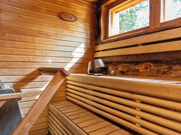 Un intérieur en bois avec une fenêtre, un gobelet en métal et un banc en bois.