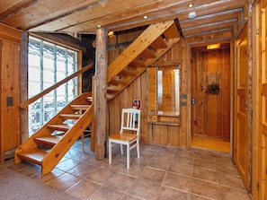 Un intérieur en bois avec un escalier, une chaise et une porte.