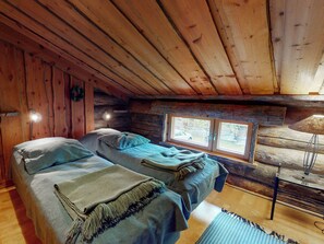 A cabin with two beds, a window, and a lamp.