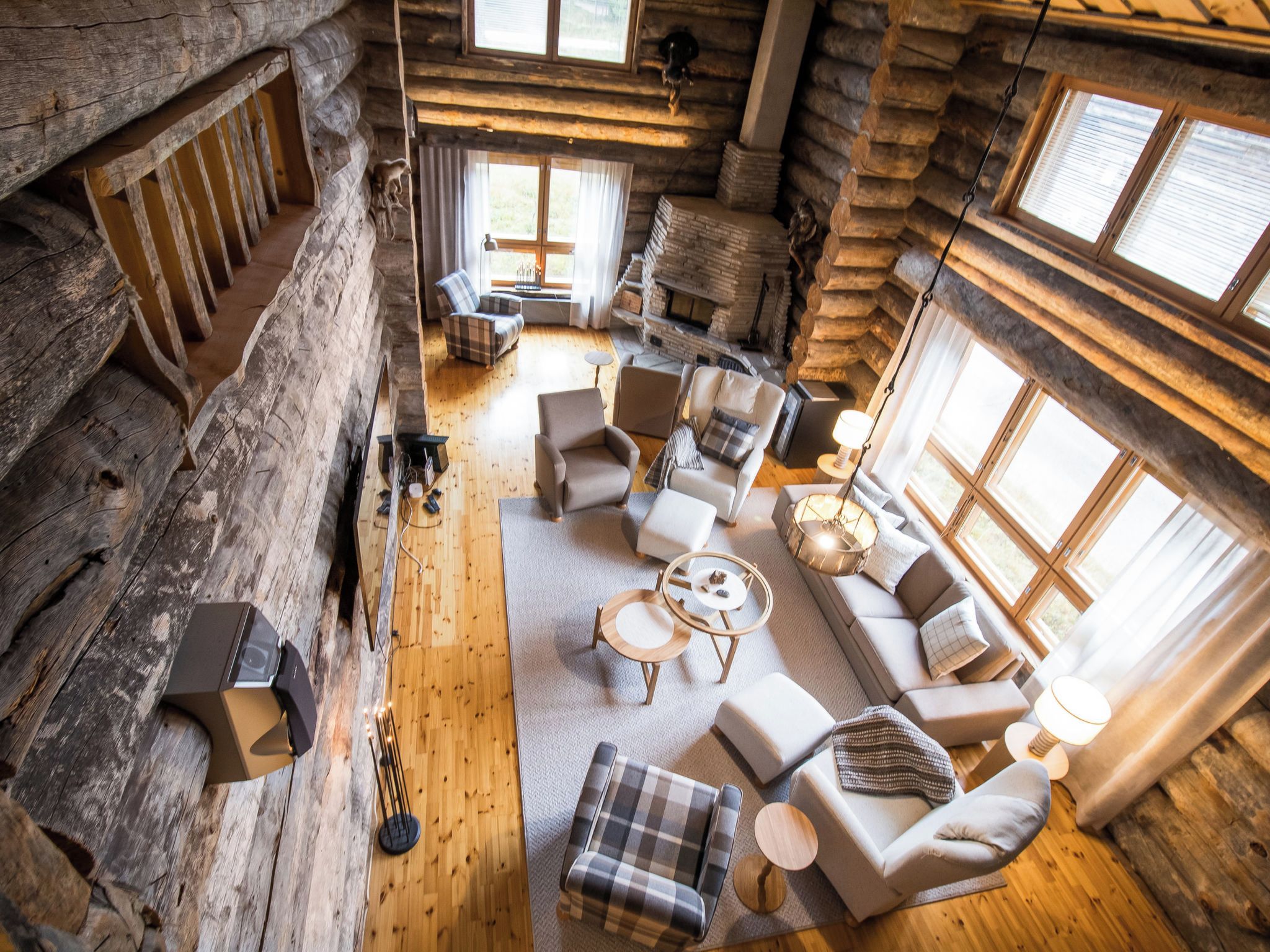 A log cabin interior with a fireplace, wooden floors, and a cozy seating area.