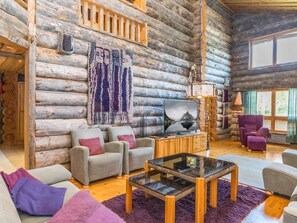 A log cabin interior with a TV, sofas, a glass coffee table, and a large window. - Waskooli saaga by Interhome (Inari)