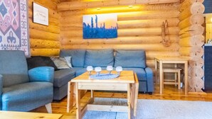 A log cabin interior with a sofa, a table with candles, and a painting on the wall. - Oton kämppä by Interhome (Inari)