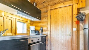 A modern kitchen with wooden cabinetry, stainless steel appliances, and a built-in oven. - Oton kämppä by Interhome (Inari)