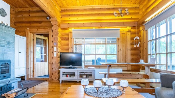 A log cabin interior with a fireplace, a television, and a dining area with a table and chairs. - Oton kämppä by Interhome (Inari)