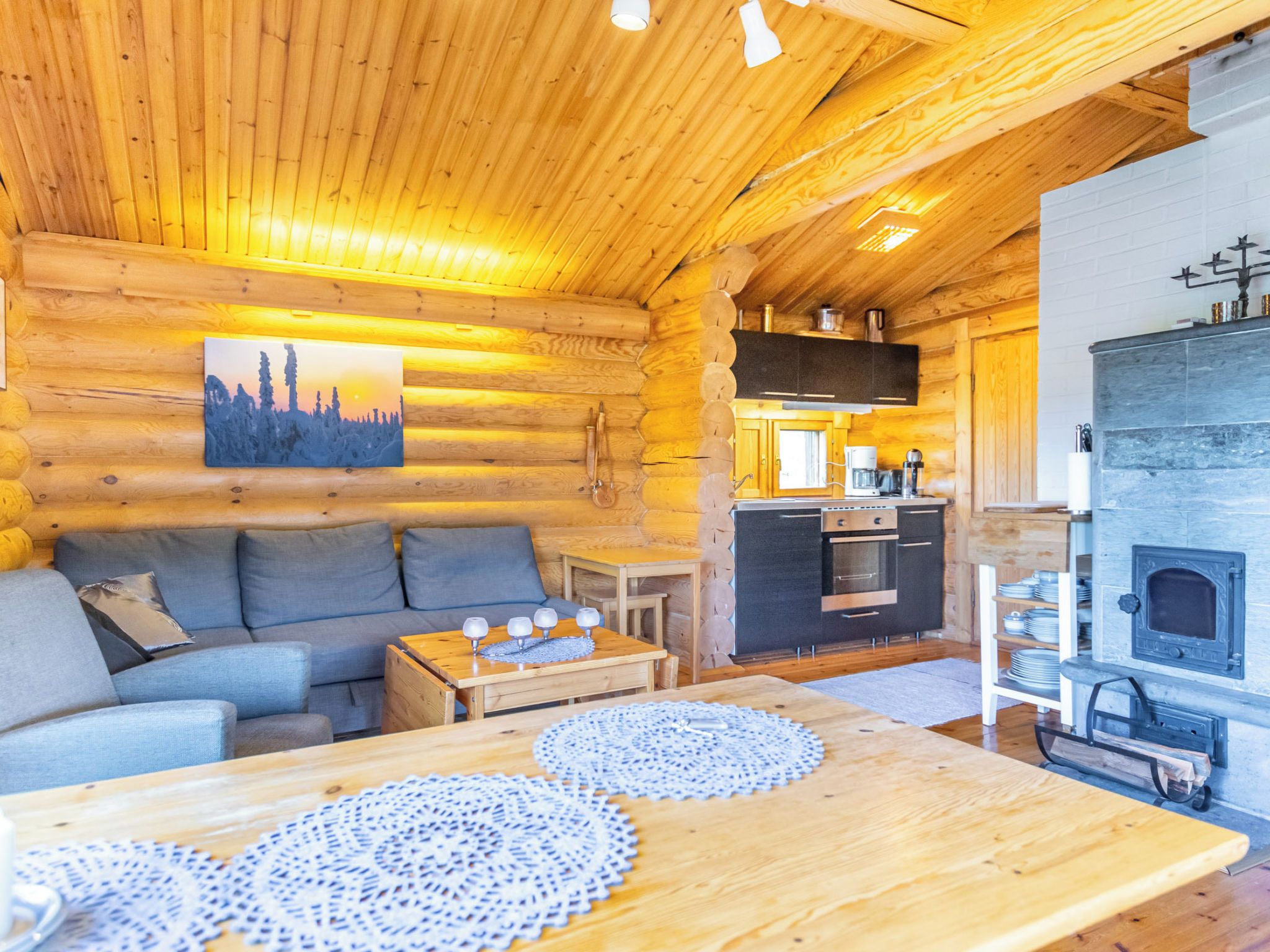 A cozy log cabin interior with a sofa, coffee table, and a fireplace.