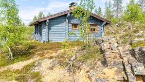 A log cabin with a wooden roof and windows, surrounded by trees and rocky terrain. - Oton kämppä by Interhome (Inari)
