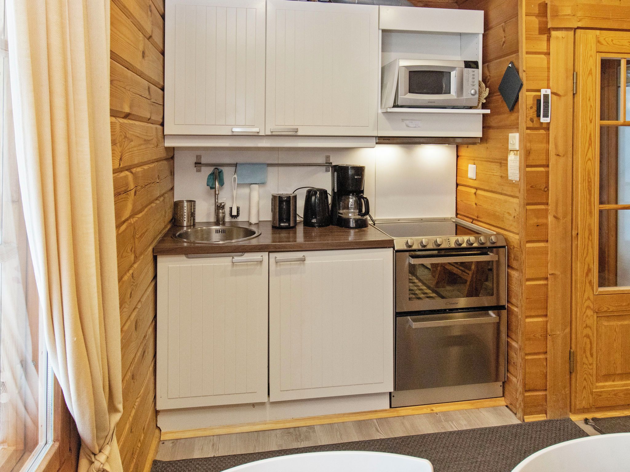 A compact kitchen with a microwave, coffee maker, and oven.