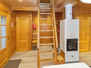 Un intérieur en bois avec un escalier en bois, une cheminée blanche et un extincteur fixé au mur.