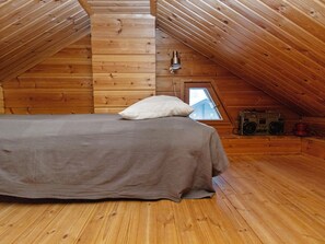 A cozy attic bedroom with a wooden floor, a bed with a pillow, a window, and a vintage radio. - Ressipysäkki 1 by Interhome (Inari)