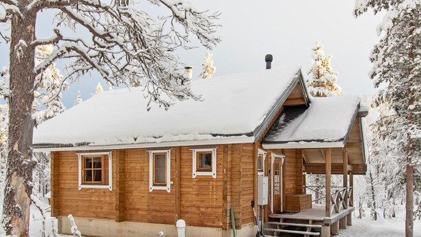 A wooden cabin with a snow-covered roof, a porch, and a chimney. - Ressipysäkki 1 by Interhome (Inari)