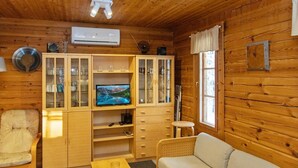 A cozy cabin interior with wooden walls, a television on a wooden cabinet, a sofa, a small table, and a window with curtains. - Ressipysäkki 1 by Interhome (Inari)