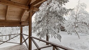 A wooden deck with a metal railing, surrounded by snow-covered trees. - Ressipysäkki 1 by Interhome (Inari)