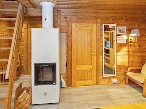 L’intérieur d’une cabane en bois, avec un poêle à bois, une porte, un miroir et une chaise.