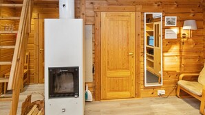 A wooden cabin interior with a wood stove, wooden shelves, a mirror, and a sofa. - Ressipysäkki 1 by Interhome (Inari)