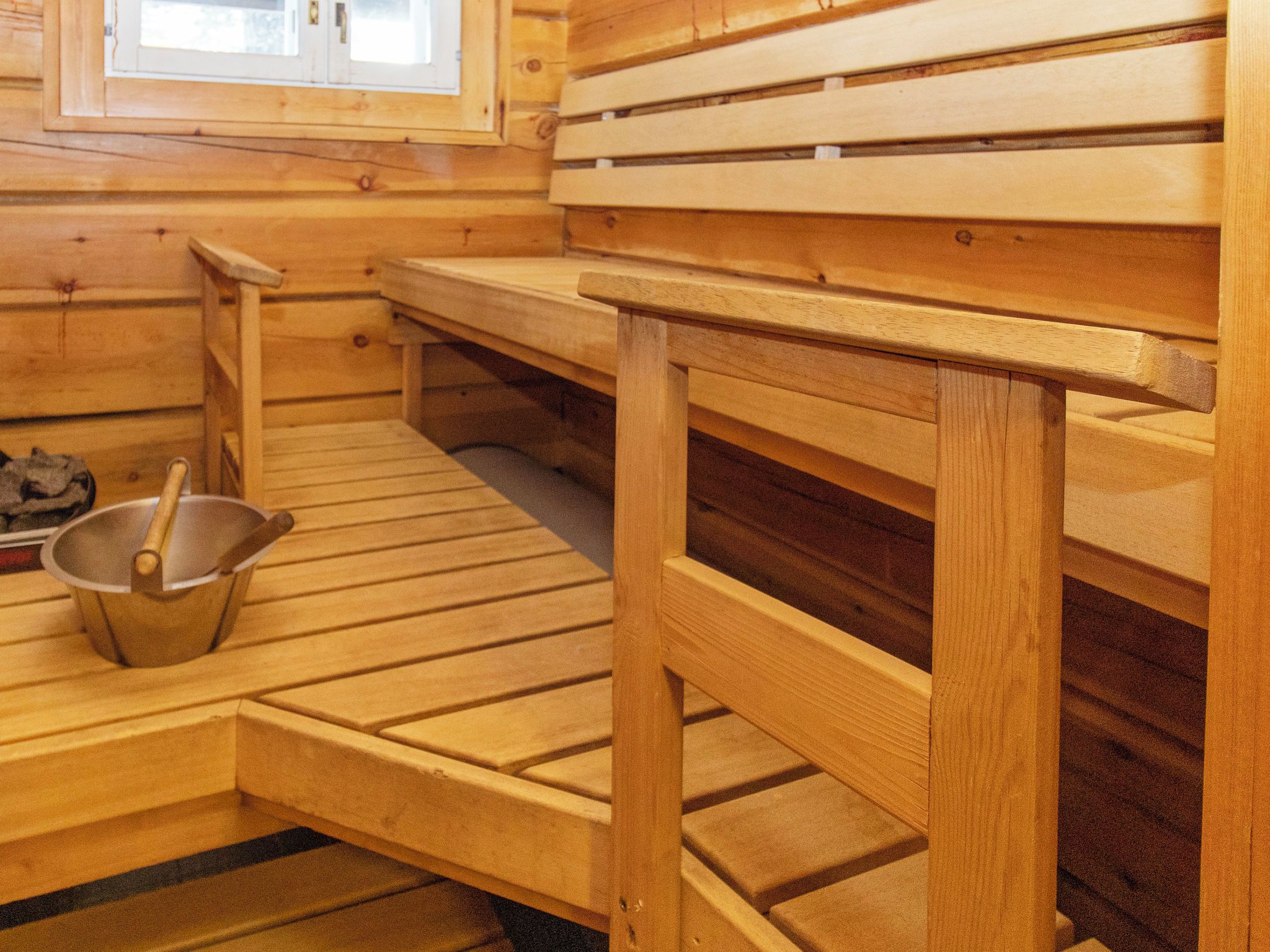 A wooden sauna with benches and a bucket.
