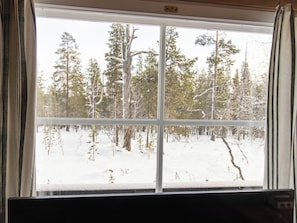 Ein Fenster mit Blick auf einen verschneiten Wald.