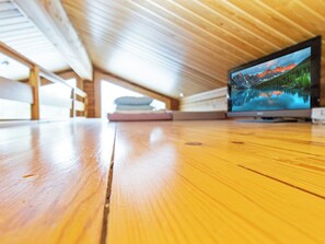 A wooden floor with a television displaying a mountain landscape.