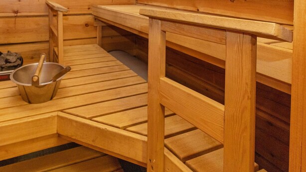 Uma sala de sauna com bancos de madeira e um balde de metal.