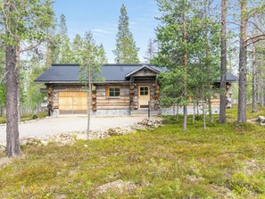 A log cabin with a garage, surrounded by trees.