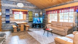 A cozy log cabin interior with a wooden ceiling, a television, a sofa, and a dining table. - Laanikelo by Interhome (Inari)