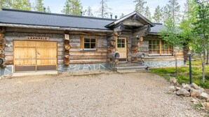 A log cabin with a stone foundation, a wooden door, and a sign reading "LAANIKELO". - Laanikelo by Interhome (Inari)