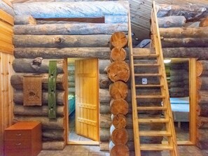 A log cabin interior with a wooden ladder, a door leading to another room, and a birdhouse on the wall. - Laanikelo by Interhome (Inari)