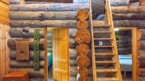 A log cabin interior with a wooden ladder leading to a loft area, a wooden door, and a small wooden cabinet with a fish design. - Laanikelo by Interhome (Inari)