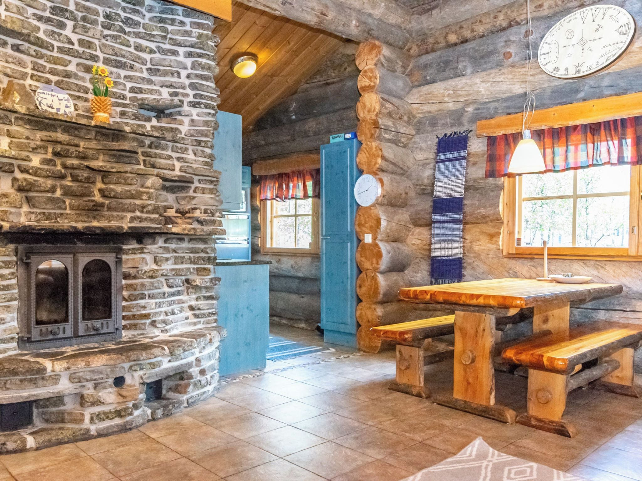 A rustic interior with a stone fireplace, wooden benches, and a blue door.
