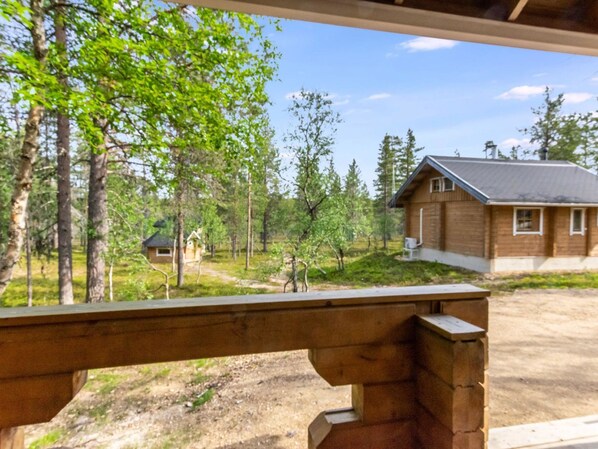 Une terrasse en bois offrant une vue sur un chalet situé dans une zone boisée.