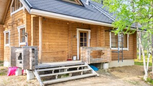 A wooden cabin with a gabled roof, a front porch, and a chimney.